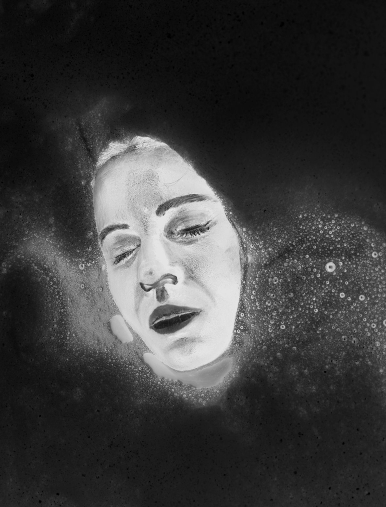 Czarno-biała zdjęcie: na ciemnym, abstrakcyjnym tle jakby wyłaniająca się z mroku kobieca twarz, bez włosów; twarz ma lekko rozchylone usta, zamknięte oczy, twarz otaczają różnej wielkości białe smugi i drobne plamy, niby mgławica gwiazd.