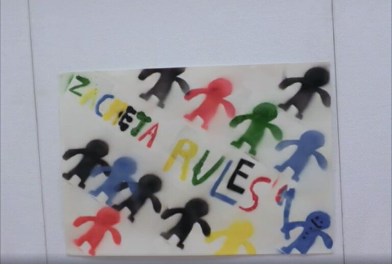 zdjęcie pracy zrobionej na warsztatach dla dzieci: kolorowe ludziki namalowane sprayem. Na środku napis 