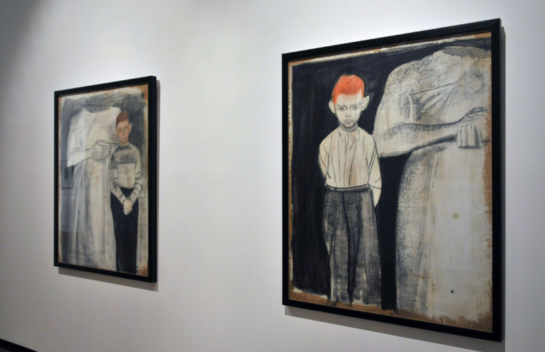 zdjęcie: na ścianie wiszą dwa obrazy Andrzeja Wróblewskiego. Na każdym dwie postaci: dorosła postać pokazana tylko od szyj w dół oraz młody chłopiec z rudymi włosami