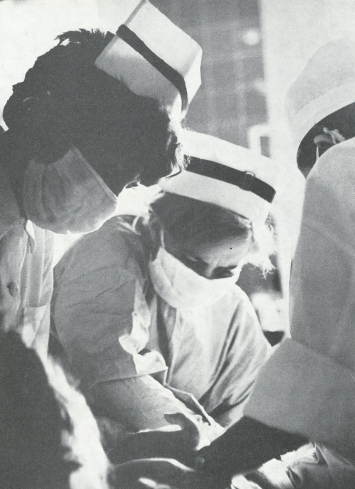 5fa5395d52b5d Czarno-białe zdjęcie z lat 60-tych. Trzy pielęgniarki w maseczkach pochylają się nad pacjentem