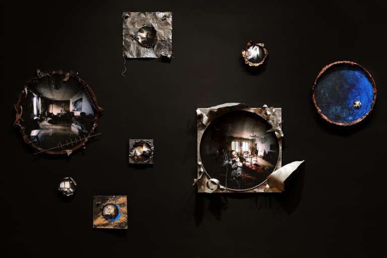 Kadr z filmu. Na czarnym tle różnej wielkości i kształtu metalowe ramy ze zdjęciami w środku.