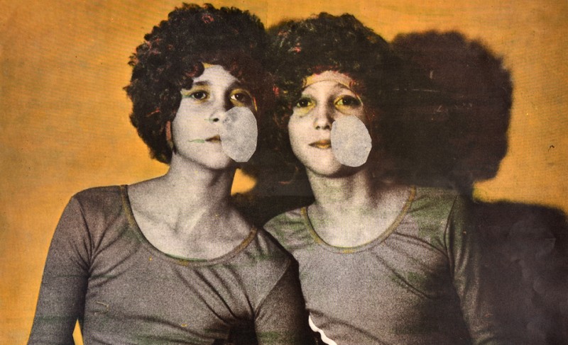 na zdjęciu: siedzą dwie młode osoby, podobne do siebie ubrane w takie same koszulki i peruki. Zdjęcie kolorowane i postarzone