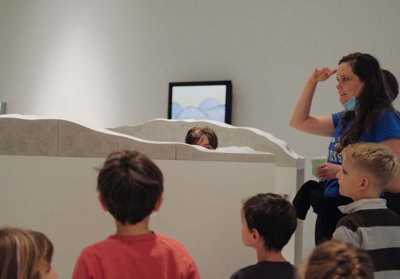 edukatorka wraz z grupą dzieci przyglądają się rzeźbom na wystawie 
