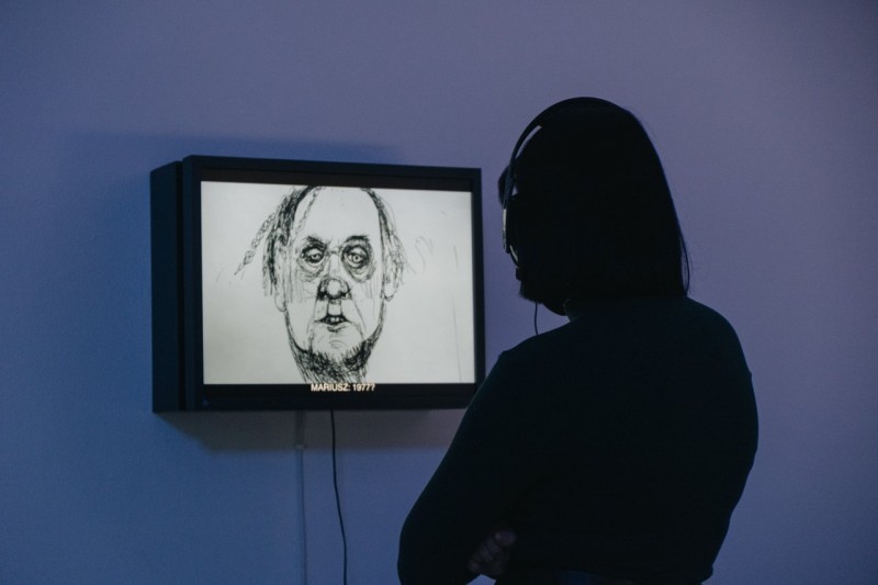 Postać w słuchawkach wpatrująca się w ekran z animacją.