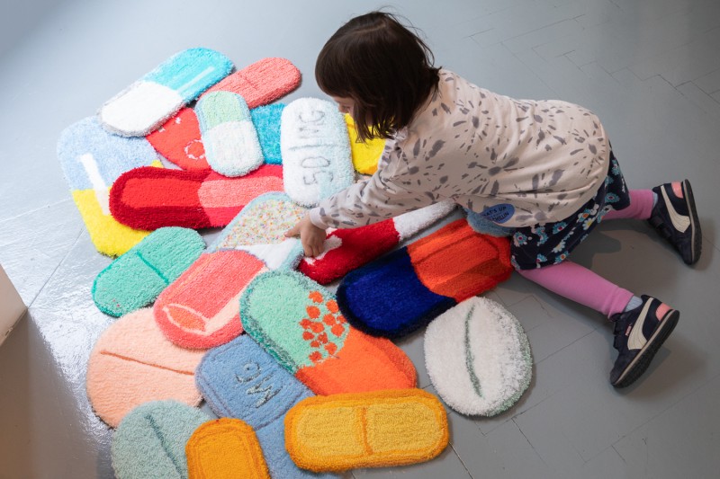 Dziecko układające na podłodze dywaniki w kształcie kolorowych leków.