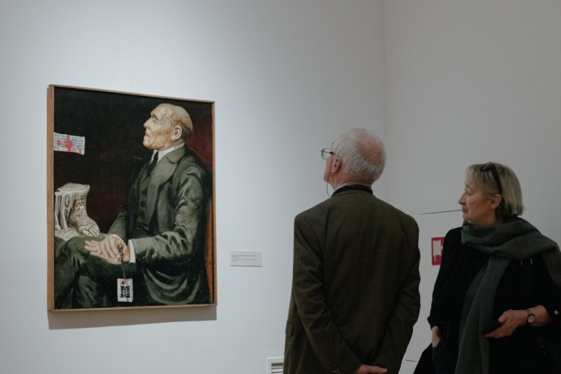 Dwie osoby oglądające obraz na wystawie.