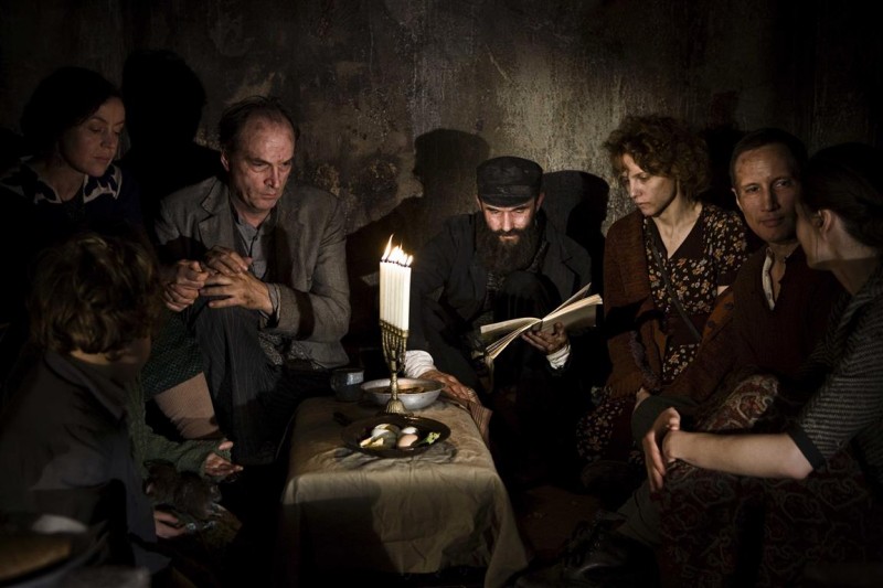 Kadr z filmu Agnieszki Holland "W ciemności", grupa ludzi zgromadzona przy zapalonej lampce.