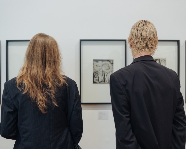 Dwie osoby wpatrujące się w rysunek na wystawie.