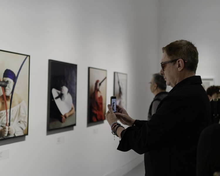 widok wystawy, osoba robiąca zdjęcie telefonem jednej z prac na ścianie.