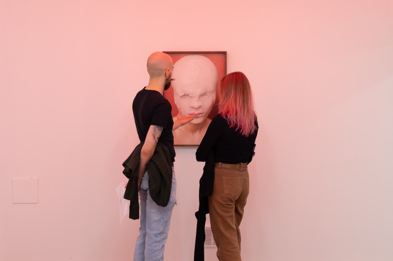 Dwie osoby oglądające obraz na ścianie w przyćmionym świetle.