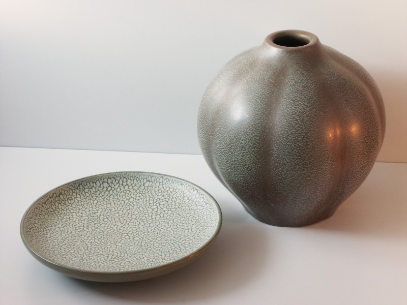 Photo of pottery, cream plate on the left and a pitcher in a similar color scheme. 