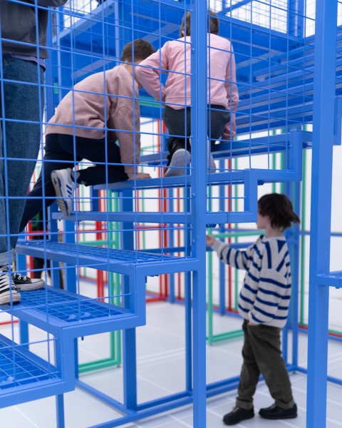 Zdjęcie dzieci wspinających się po niebieskiej metalowej konstrukcji.