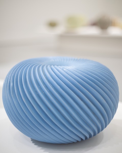 zdjęcie; ceramiczna rzeźba o kształcie kulistego niebieskiego wazonu z wypukłą, spiralną fakturą powierzchni.