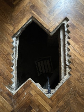 Czarna dziura w parkiecie, prowadząca do pomieszczenia pod podłogą.