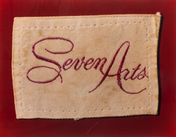Fragment metki odzieżowej, czerwony napis na kremowym materiale