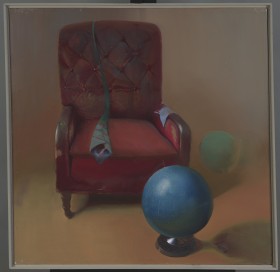 Obraz realistyczny w kwadracie. W pustej jasnej przestrzeni fotel w czerwonym obiciu, na nim zielony krawat. Przed fotelem błękitna kula na podstawce przypominająca globus.