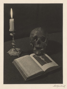Rozłożona książka z ilustracją ukrzyżowanego Chrystusa. Na niej czaszka. Obok świecznik z palącą się świecą.
